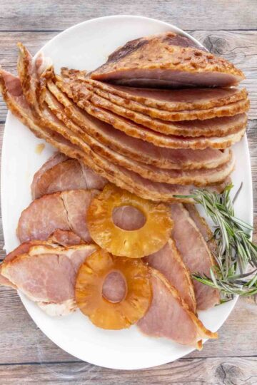 slow cooker ham slices with pineapple slices on a white platter.
