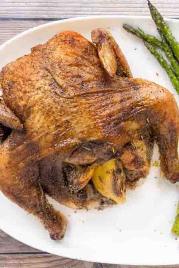 Plate with a cornish game hen and a side of asparagus.