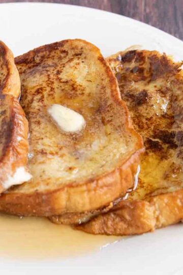 A plate of French toast with butter and maple syrup.