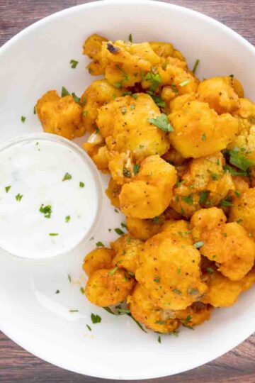 Bowl of Buffalo cauliflower bites with a side of blue cheese.